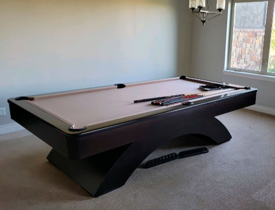 Pro pool table with beige cloth and pool sticks on top
